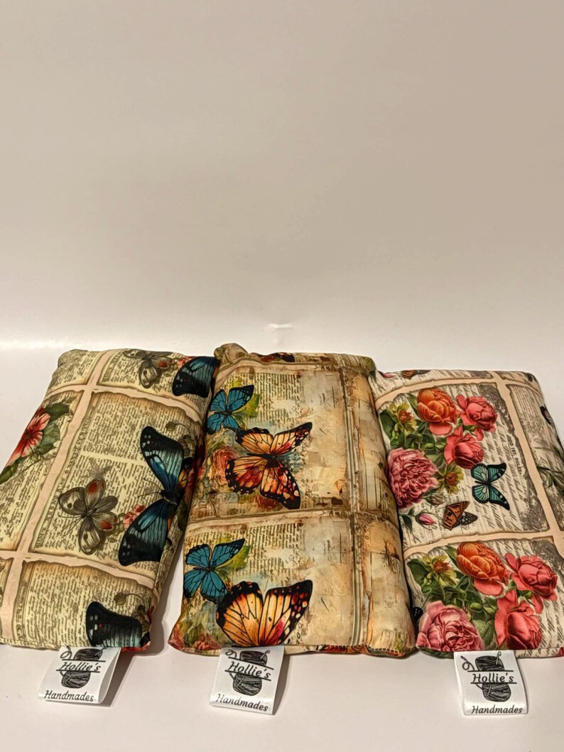 May include: Three rectangular pillows with butterfly and floral patterns. The pillows feature a vintage newspaper print background. The butterflies are in shades of blue, orange, and brown. Each pillow has a tag that reads "Hollie's Handmades."
