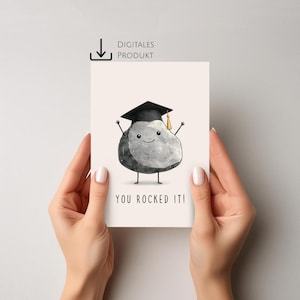 Op de afbeelding: Een afstudeerkaart met een cartoon rotskarakter met een zwarte afstudeerhoed met een gouden kwast. De kaart heeft de tekst "YOU ROCKED IT!" en de woorden "DIGITALES PRODUKT" met een downloadpictogram.
