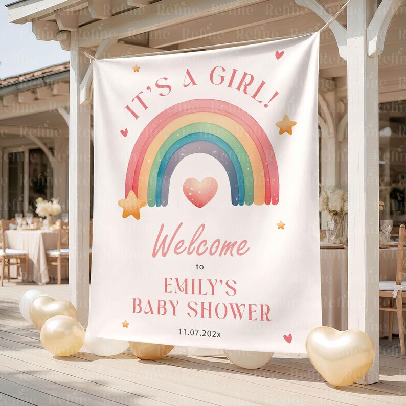 Op de afbeelding: Een witte banner met de tekst "IT'S A GIRL!" en "Welcome to EMILY'S BABY SHOWER 11.07.202x". De banner heeft een regenboog, sterren en een hart ontwerp, perfect voor een babyshower.
