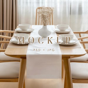 May include: A white table runner with a wooden table and four white plates and bowls. A vase with white flowers sits in the center of the table. The text "MOCKUP" and "PSD + JPG" is printed on the table runner.