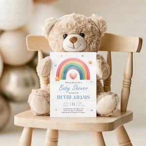 Peut inclure: Une invitation &agrave; une baby shower avec un arc-en-ciel, tenue par un ours en peluche sur une chaise en bois. L'invitation comprend le texte "Baby Shower" et les d&eacute;tails de l'&eacute;v&eacute;nement.