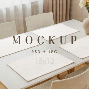 Op de afbeelding: Een witte tafelsetting mockup met vier rechthoekige placemats. De tekst "MOCKUP" wordt weergegeven boven "PSD + JPG" en "18x12". De scène omvat stoelen, een vaas met bloemen en een raam met gordijnen.