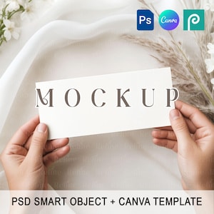 May include: A white rectangular card with the word "MOCKUP" in brown lettering is held between two hands. The background includes white fabric, floral elements, and icons for Photoshop, Canva, and a pen tool.
