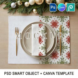 May include: A festive table setting with a white placemat, a plate, and a folded napkin. The napkin and the right side of the placemat feature a red and green snowflake pattern. A gold fork and knife are on either side of the plate. The word "MOCKUP" is printed on the plate.