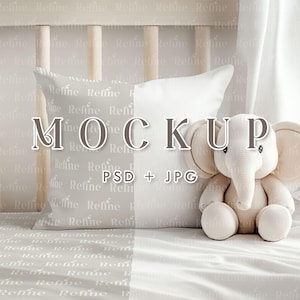 Puede incluir: Una almohada blanca con una funda de almohada estampada se encuentra sobre una cama blanca con un elefante de peluche blanco. La funda de almohada tiene el texto "Refine" repetido. El texto "MOCKUP" se superpone a la imagen. El texto "PSD + JPG" también se superpone a la imagen.