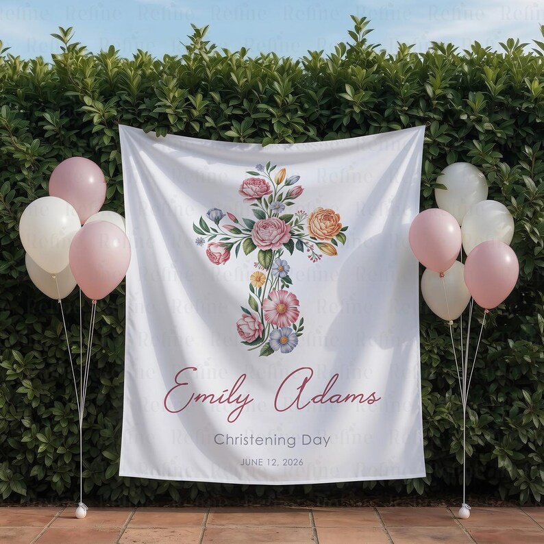 May include: White fabric backdrop with a floral cross design, featuring pink and peach roses, and other flowers. The text "Emily Adams, Christening Day, June 12, 2026" is printed on the backdrop. Pink and white balloons are on either side.