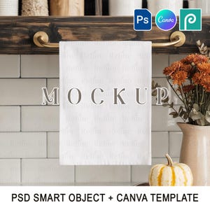 May include: A white kitchen towel mockup with the word "MOCKUP" printed on it, hanging from a dark wooden shelf with brass hardware. A small pumpkin and vase of flowers are in the background. The text "PSD SMART OBJECT + CANVA TEMPLATE" is at the bottom.