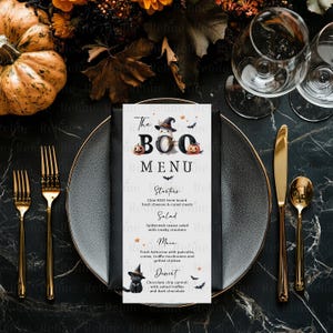 May include: A rectangular Halloween menu card titled The BOO MENU with a ghost wearing a witch hat, pumpkins, and bats. The text lists Starters, Salad, Main, and Dessert courses with spooky-themed food names, printed on a black plate with cutlery.