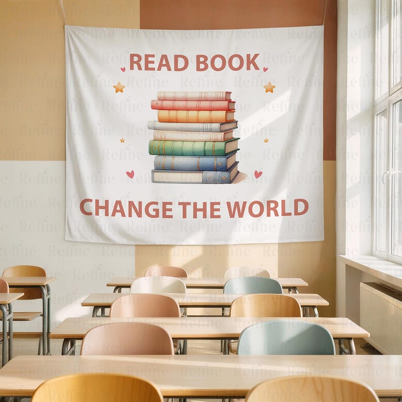 May include: White wall tapestry with the text "READ BOOK, CHANGE THE WORLD" in brown. A stack of colorful books is in the center, with star and heart accents. The scene is set in a classroom with wooden desks and chairs.