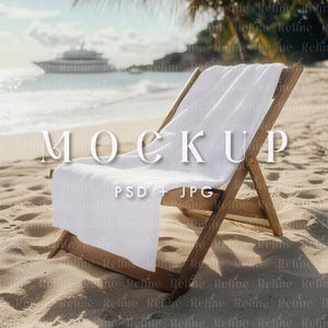 May include: A white beach towel draped over a wooden beach chair on a sandy beach. The chair is partially buried in the sand. The background shows a blue ocean and a white yacht.
