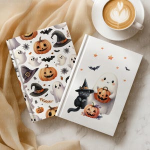 May include: Two Halloween-themed journals with white pages. One features pumpkins, ghosts, bats, and witch hats. The other shows a black cat in a witch hat, a ghost holding a pumpkin, and smaller pumpkins. A cup of coffee sits nearby.