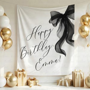 May include: A white backdrop with the words "Happy Birthday Emma!" in elegant script, accented by a large black bow illustration. Gold and white balloons and wrapped gifts complete the celebratory scene.