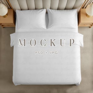 May include: An overhead shot of a bed with white bedding, including two pillows and a duvet cover. The word "MOCKUP" is displayed across the duvet cover, with "PSD + JPG" below it. Two wooden bedside tables with lamps are on either side.