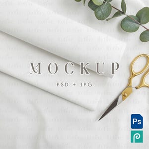 May include: A flat lay featuring white fabric rolls, gold scissors, and eucalyptus leaves. The word "MOCKUP" is displayed, along with "PSD + JPG" and two software icons. The image has a clean, minimalist aesthetic.