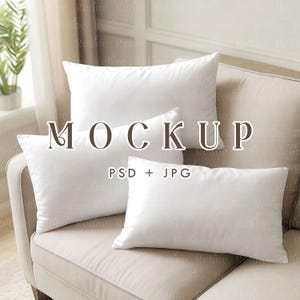 May include: Four white pillows of varying sizes arranged on a beige sofa. The pillows are rectangular and square, with a soft, smooth texture. The word "MOCKUP" is displayed in a serif font, with "PSD + JPG" below it.