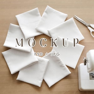 May include: A mockup featuring a collection of white fabric squares arranged in a circular pattern. The word "MOCKUP" is displayed in the center, with "PSD + JPG" below. Scissors and a sewing machine are visible.