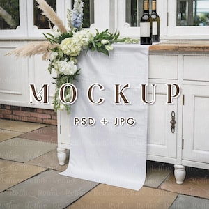 May include: A white cabinet with a white tablecloth and floral arrangement. Two wine bottles are on top of the cabinet. The text "MOCKUP PSD + JPG" is displayed on the tablecloth.
