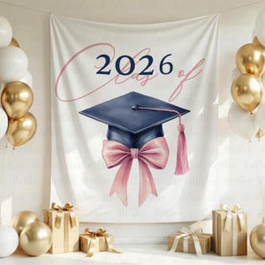 May include: A white graduation backdrop with the text "2026 Class of" in a cursive font. A navy blue graduation cap with a pink bow and tassel is featured. Gold and white balloons and wrapped gifts are also in the image.