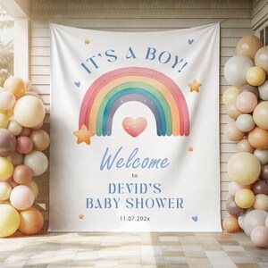 K&ouml;nnte beinhalten: Ein wei&szlig;es Banner mit dem Text "IT'S A BOY!" und "Welcome to DEVID'S BABY SHOWER" in Blau. Ein Aquarell-Regenbogen und ein Herz sind auf dem Banner zentriert, mit Stern- und Herzakzenten. Ballons in Beige-, Pfirsich- und Wei&szlig;t&ouml;nen umrahmen das Banner.