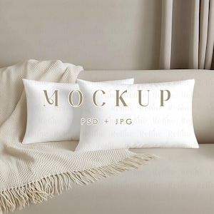 May include: Two white throw pillows on a beige couch with a white blanket. The pillows have the text "MOCKUP PSD + JPG" printed on them.