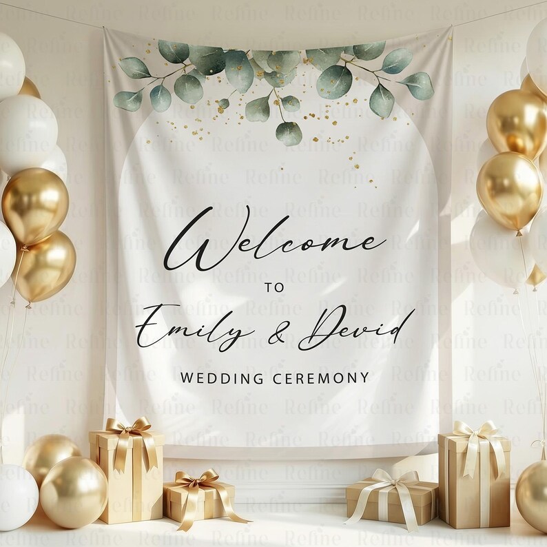May include: A white wedding ceremony backdrop with the text "Welcome to Emily & David" and "Wedding Ceremony". The backdrop is decorated with green leaves and gold accents. Gold and white balloons and wrapped gifts are also present.