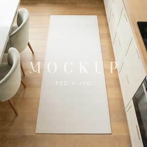 May include: A rectangular white rug on a light wood floor, positioned in a kitchen setting. The rug is centered, with a table and chairs on the left and kitchen cabinets on the right. The word "MOCKUP" is visible on the rug.