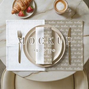 May include: A breakfast table setting with a croissant, strawberries, and a cup of coffee. A plate, napkin, and cutlery are arranged on a placemat with the word "Refine" printed on it. The word "MOCKUP" is displayed on the plate.