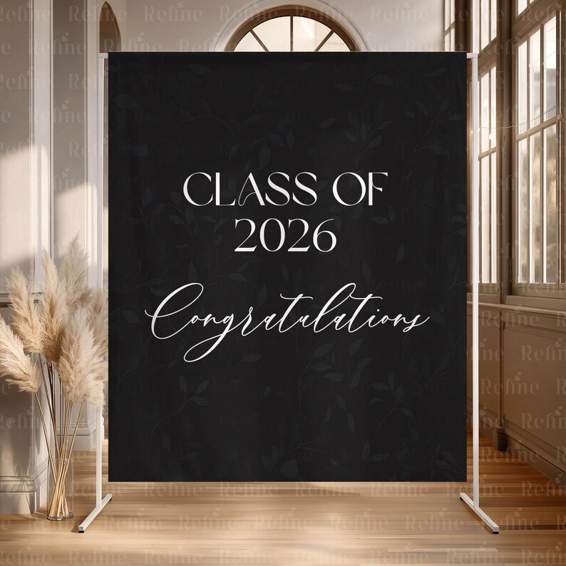 May include: A black graduation backdrop with white text that reads "CLASS OF 2026 Congratulations." The backdrop has a subtle floral pattern and is supported by a white metal frame. Perfect for graduation parties.