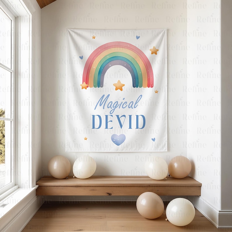 K&ouml;nnte beinhalten: Ein wei&szlig;es Banner mit einem bunten Regenbogen-Design, Sternen und dem Text "Magical DEVID" in Blau. Das Banner h&auml;ngt &uuml;ber einer Holzbank mit mehreren Ballons in neutralen Farben.