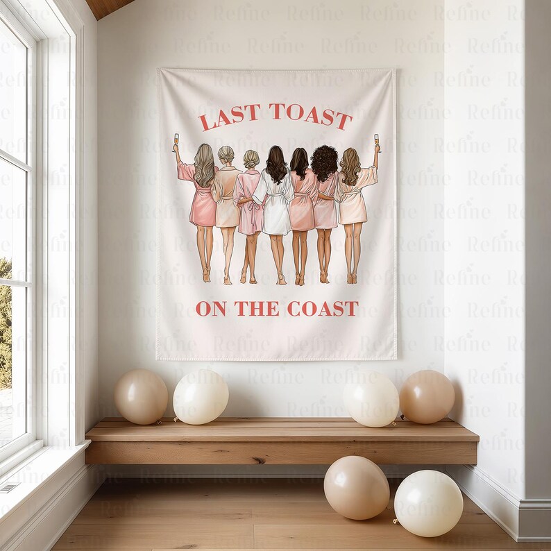 K&ouml;nnte beinhalten: Ein wei&szlig;es Wandtuch mit dem Text "LAST TOAST ON THE COAST" in Rot. Das Wandtuch zeigt sieben Frauen in Badem&auml;nteln, die mit Gl&auml;sern ansto&szlig;en. Beige Luftballons liegen auf einer Holzbank.