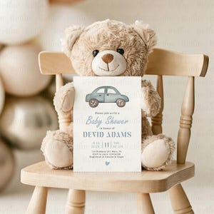 Peut inclure: Une invitation de baby shower avec une illustration de voiture bleue. L'invitation, tenue par un ours en peluche sur une chaise en bois, comprend la date, l'heure, le lieu et les d&eacute;tails RSVP. Le texte dit "Baby Shower" dans une &eacute;criture &eacute;l&eacute;gante.
