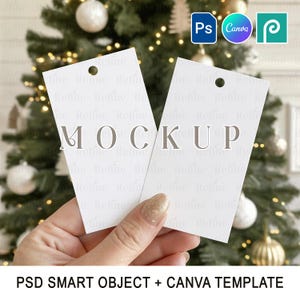 Könnte beinhalten: Zwei weiße rechteckige Etiketten mit dem Aufdruck "MOCKUP" werden vor einem Weihnachtsbaum gehalten. Die Etiketten haben oben ein Loch. Der Text "PSD SMART OBJECT + CANVA TEMPLATE" steht unten.