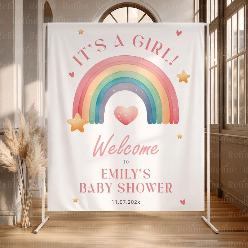 May include: A white banner with the text "IT'S A GIRL!" and "Welcome to EMILY'S BABY SHOWER" in pink. A watercolor rainbow, heart, and stars decorate the banner. The date "11.07.202x" is also included.