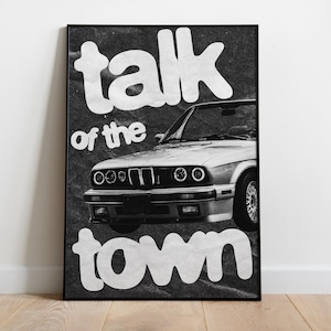 May include: Black and white poster featuring a vintage convertible car. The words "talk of the town" are in large, white, distressed font. The car is centered, with its headlights and front grill visible.
