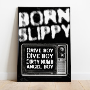 May include: Black and white poster with the text "BORN SLIPPY" in a bold, pixelated font. Below the text is a black and white image of a vintage television with the text "DRIVE BOY, DIVE BOY, DIRTY NUMB, ANGEL BOY" displayed on the screen.