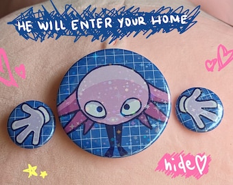 May include: Pink plush toy with a blue and white grid pattern button featuring a pink axolotl with a glittery finish. The text "He loves you!" is written in pink on the toy. The text "He will enter your home" is written in black on the toy. The text "hide" is written in pink on the toy.