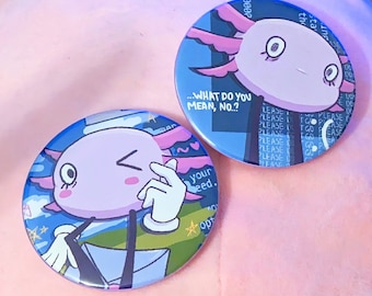 May include: Two round blue and white button pins with a cartoon axolotl wearing a hat and a blue background. The text on the pins reads "...WHAT DO YOU MEAN, NO...?" and "your need."