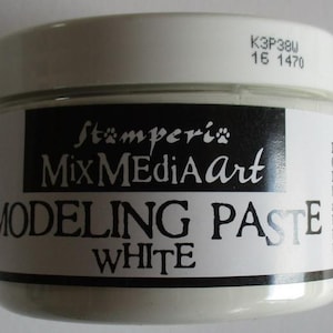Op de afbeelding: Een witte pot Stamperia Mix Media Art Modeling Paste. De pot heeft een wit deksel en een zwart etiket met witte tekst met de tekst "MODELING PASTE WHITE". De pot heeft ook de tekst "K3P38U 16 1470" op het deksel.