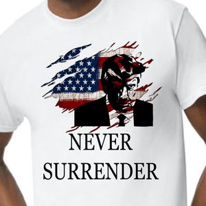 May include: White t-shirt featuring a graphic of a man's silhouette with an American flag design. The text "NEVER SURRENDER" is printed below the graphic in a bold, black font. The shirt has a crew neck and short sleeves.
