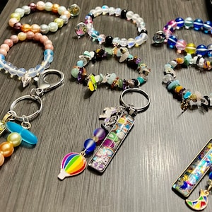 Llaveros, pinzas para carteras y pulseras con temáticas alegres, pacíficas y playeras