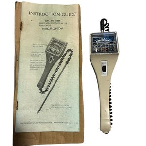 May include: A white light and moisture meter for plants with a black dial and a probe. The meter has a black and white instruction guide with the text "INSTRUCTION GUIDE", "CAT. NO. 63406", "LIGHT AND MOISTURE METER FOR PLANTS", "MICRONTA", "EASY TO READ METER FACE", "LIGHT SENSOR FOR ACCURATE READINGS", "MOISTURE LIGHT SELECTOR SWITCH UP FOR MOISTURE DOWN FOR LIGHT READINGS", "TAPERED SOIL PROBE FOR MOISTURE TESTING", "CUSTOM MANUFACTURED FOR RADIO SHACK, A DIVISION OF TANDY CO."