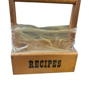 May include: A wooden recipe box with a handle and a clear plastic insert. The box is labeled "RECIPES" in black lettering.