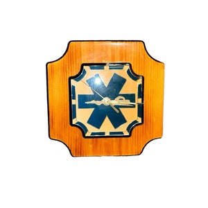May include: A wooden clock with a blue and gold star design on the face. The clock is in a square frame with rounded corners.
