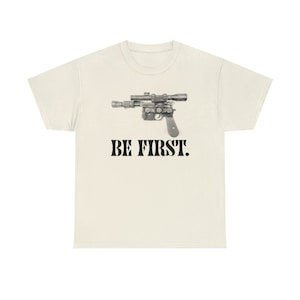 May include: A white t-shirt with a black and white image of a blaster and the text "BE FIRST."