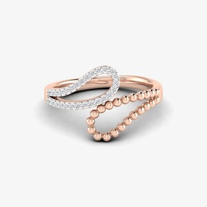 May include: A rose gold ring with a delicate, curved design set with small diamonds. The ring features a beaded detail on one side.
