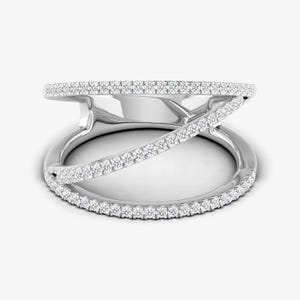 Puede incluir: Un anillo de plata con un dise&ntilde;o &uacute;nico. El anillo presenta una banda que rodea el dedo, con una segunda banda que la cruza. Ambas bandas est&aacute;n incrustadas con peque&ntilde;as piedras brillantes, creando un efecto deslumbrante. El anillo est&aacute; sobre un fondo blanco.