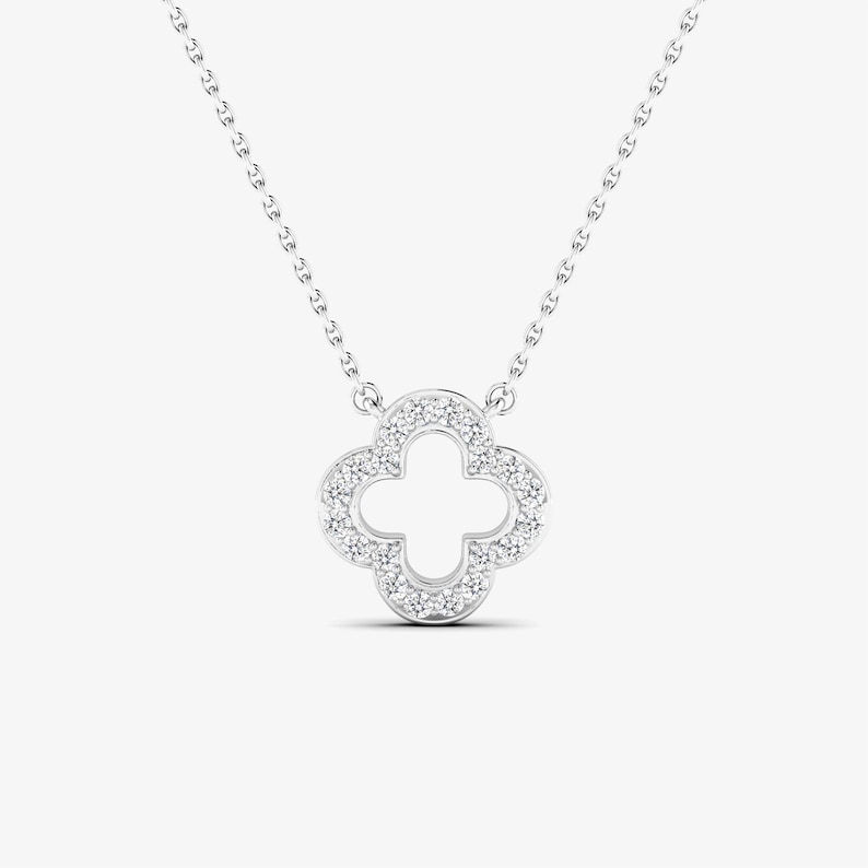 May include: A silver necklace with a four-leaf clover pendant encrusted with small diamonds.