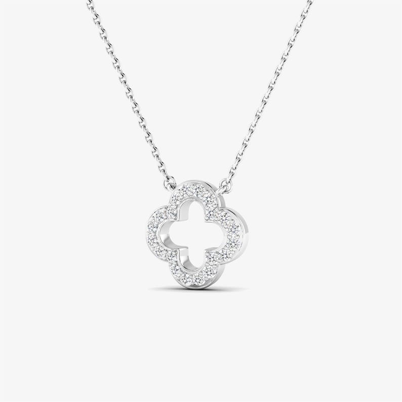 May include: A silver necklace with a four-leaf clover pendant encrusted with clear cubic zirconia stones.