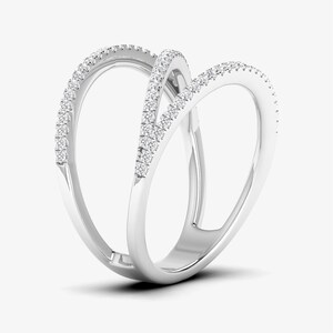Puede incluir: Un anillo de oro blanco con un dise&ntilde;o abierto &uacute;nico. El anillo presenta tres bandas entrelazadas, cada una adornada con peque&ntilde;os diamantes brillantes. Los diamantes capturan la luz, creando una exhibici&oacute;n brillante. El anillo es una joya moderna y elegante.