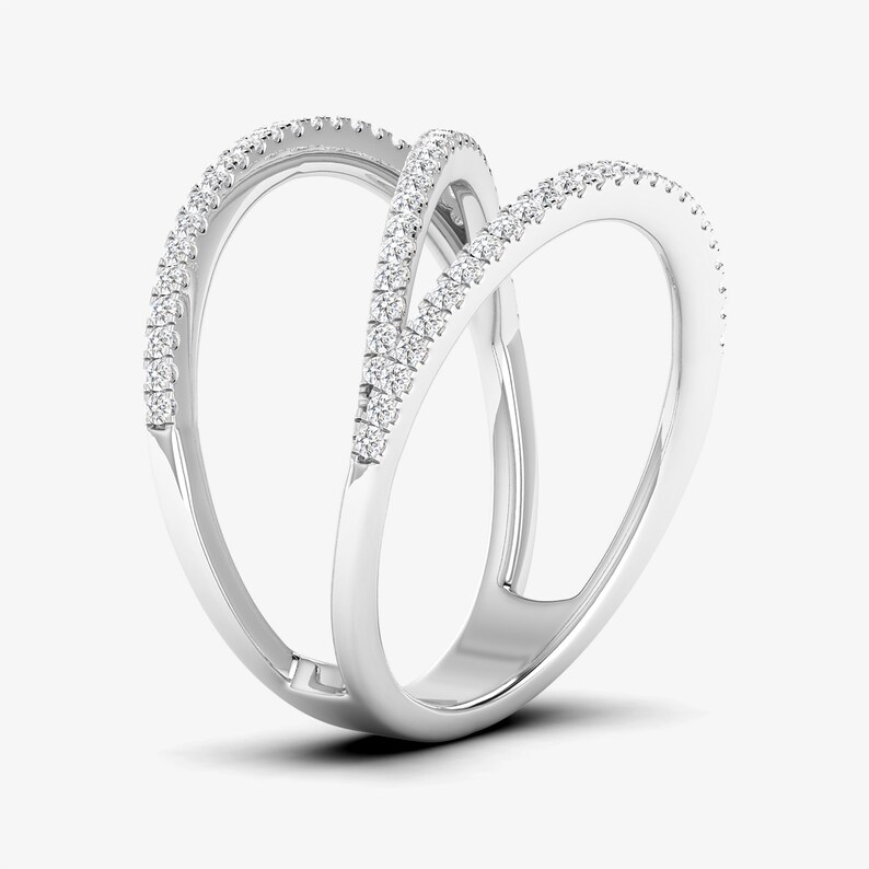 Puede incluir: Un anillo de oro blanco con un dise&ntilde;o abierto &uacute;nico. El anillo presenta tres bandas entrelazadas, cada una adornada con peque&ntilde;os diamantes brillantes. Los diamantes capturan la luz, creando una exhibici&oacute;n brillante. El anillo es una joya moderna y elegante.